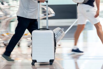 Busy airport, passengers walking across the frame with luggage